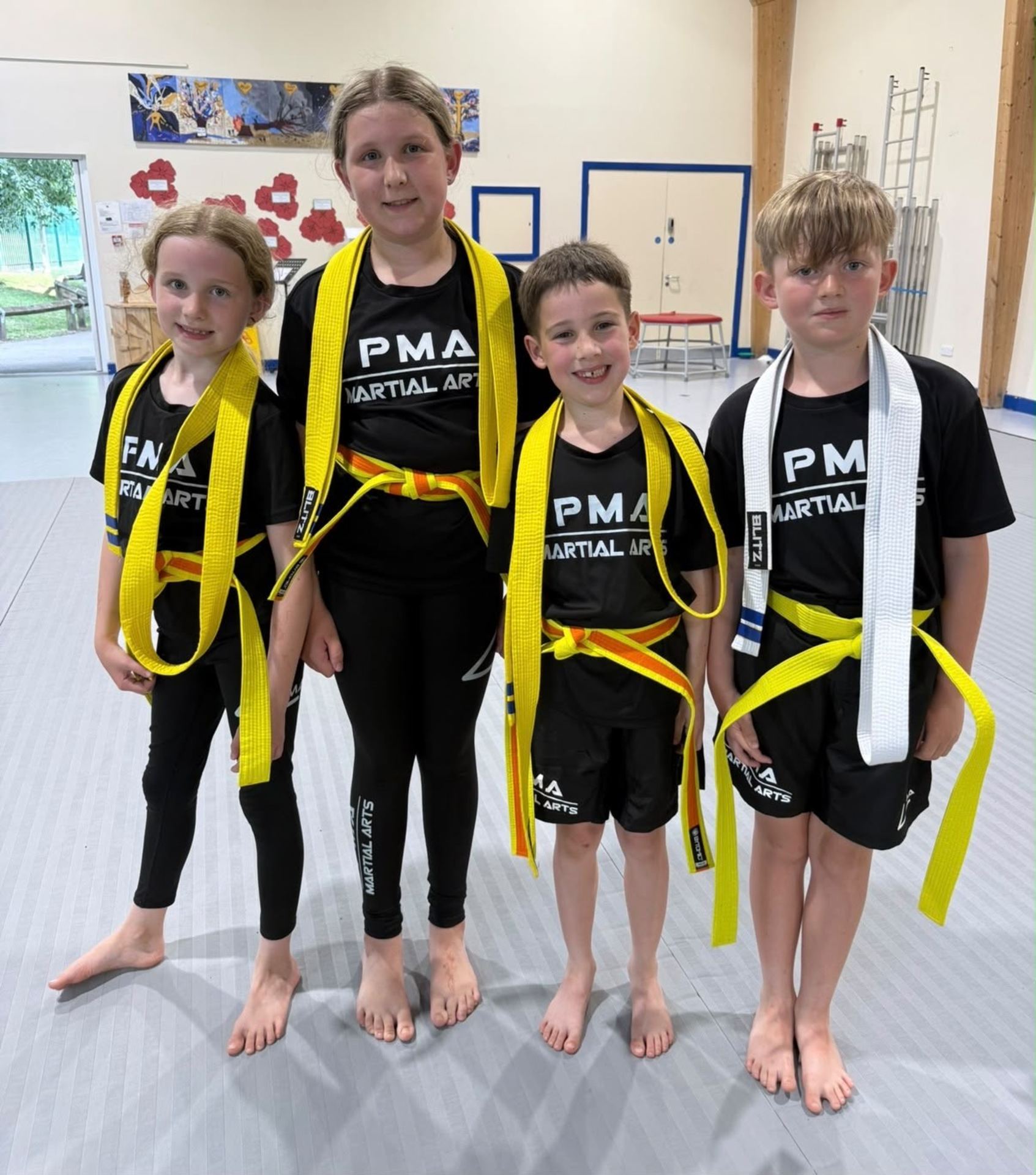 Four young PMA students on the mats with their new belts