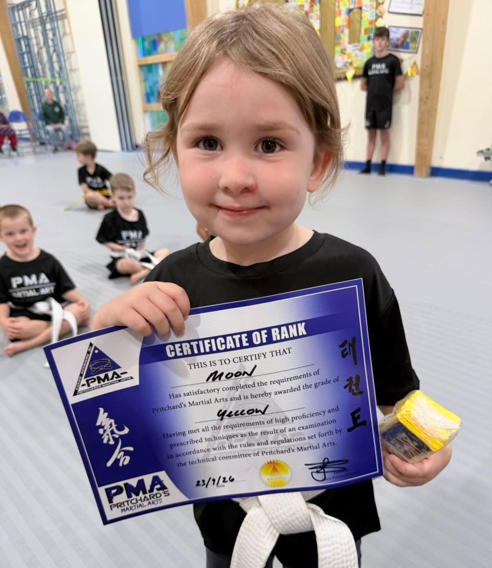 Little Dragons student holding her yellow belt Certificate of Rank