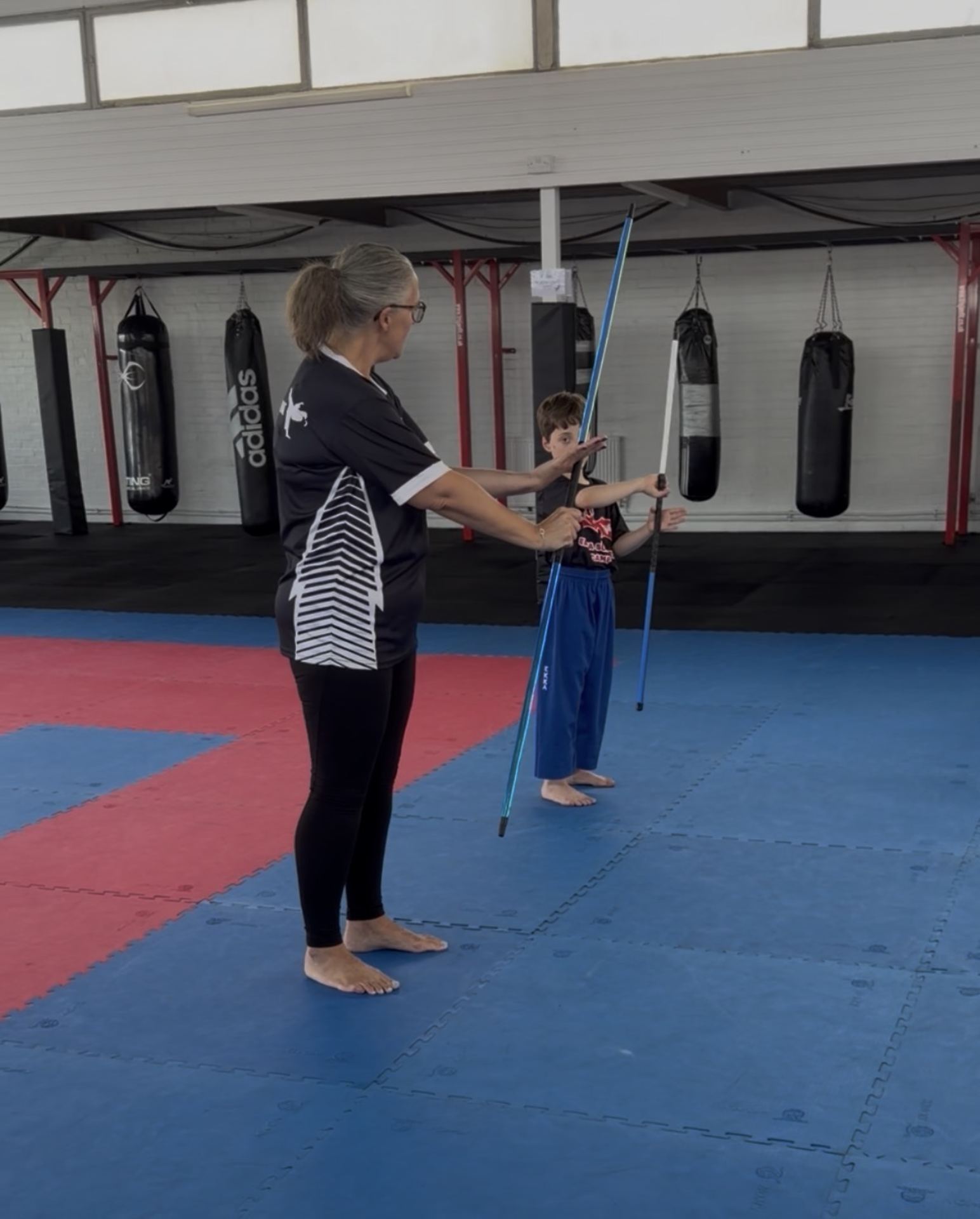 Instructor guiding a young beginner through bo staff positions