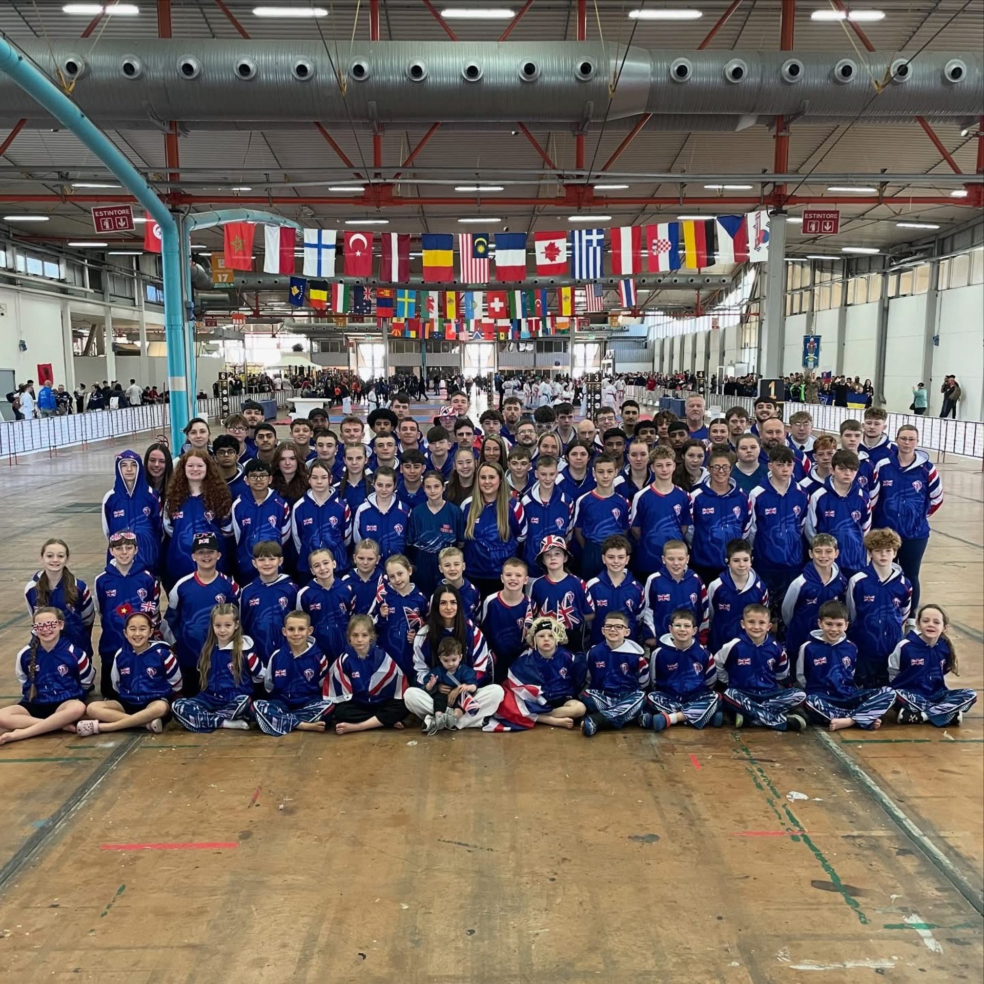 Team GB squad in competition hall under international flags