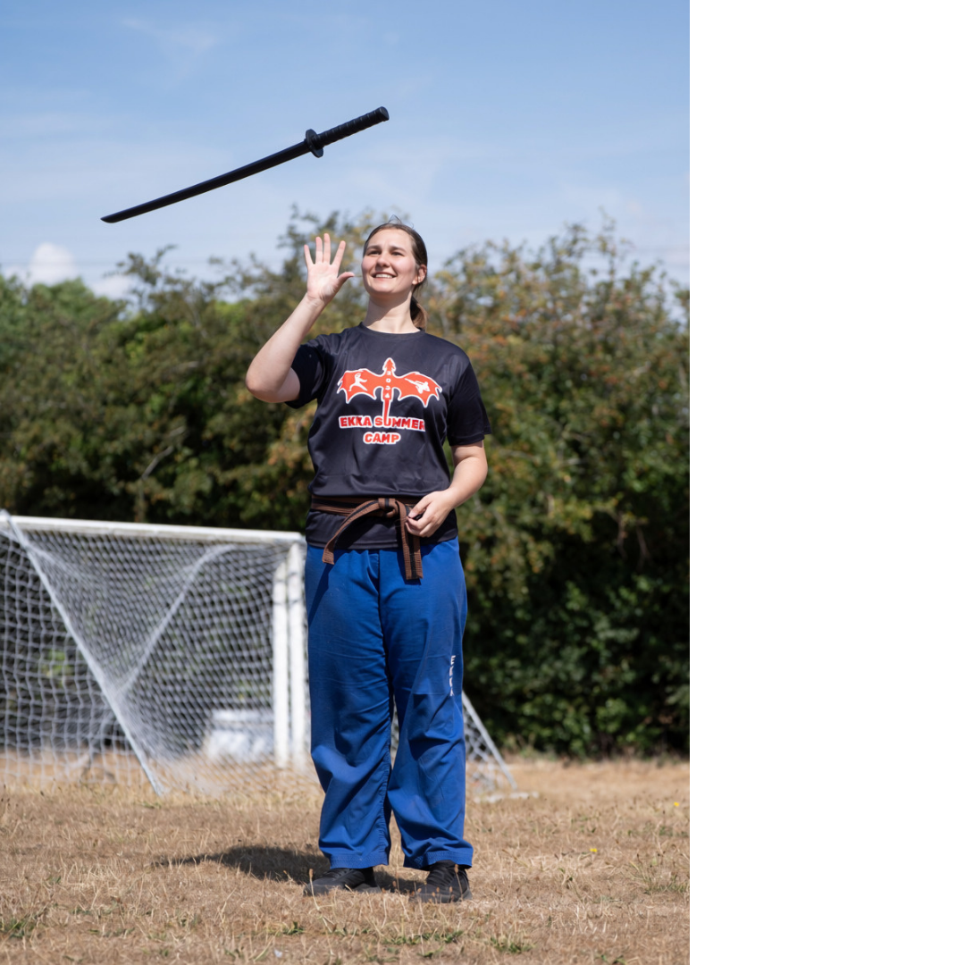 Student tossing a practice sword outdoors