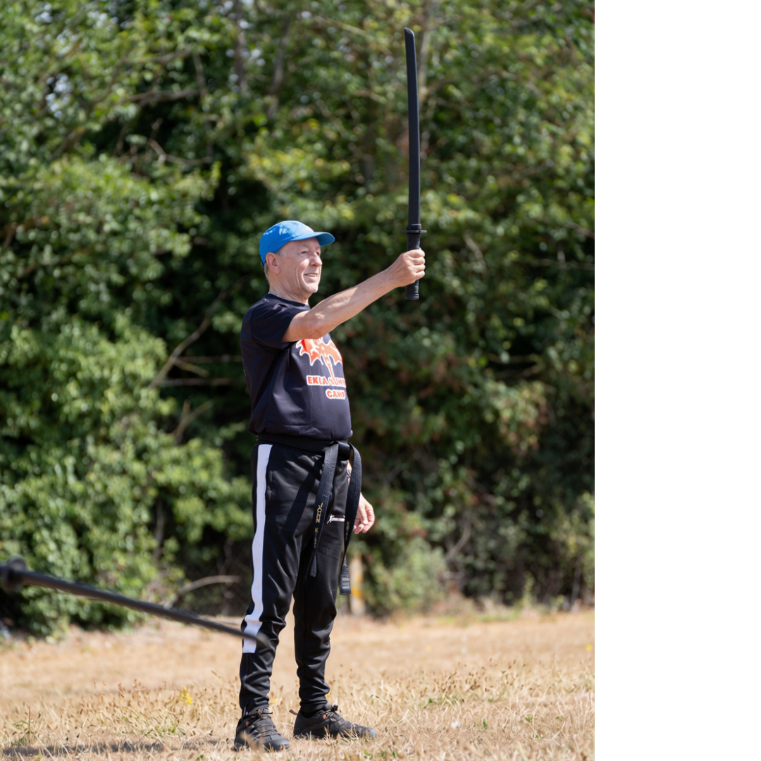 Black belt holding a practice sword aloft